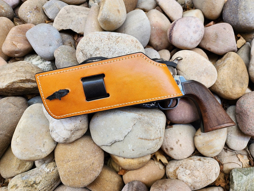 Bottom end of angel eyes holster displaying the russet leather tongue as it lays on a bed of rocks.