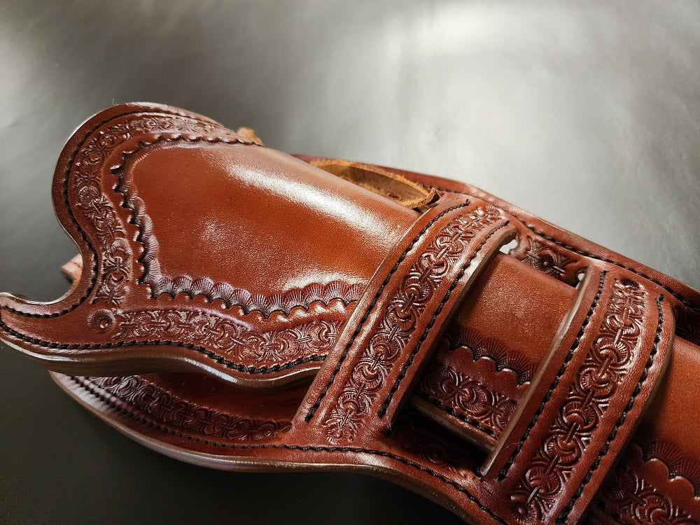 Close up view of the front side of the holster prominently displaying the double Mexican loop collar and the intricate tooling on the brown leather.