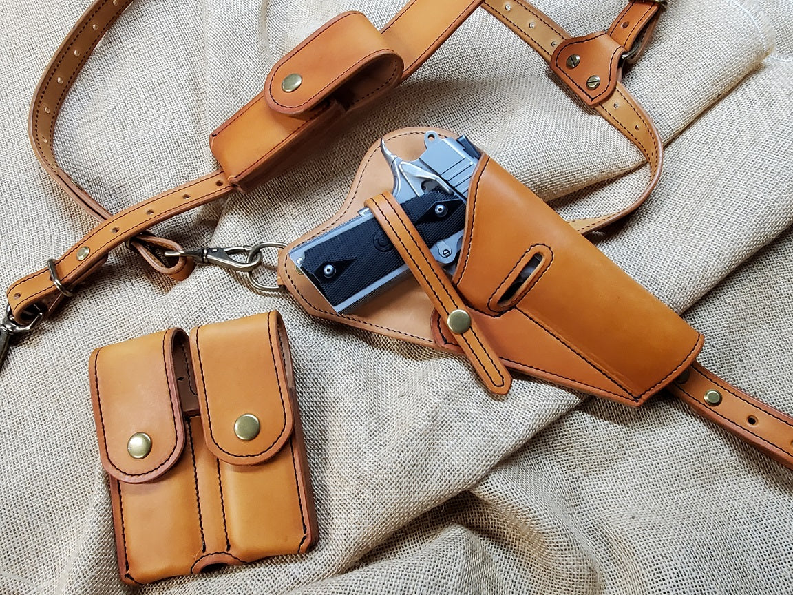 Russet shoulder holster featuring solid brass hardware with M1911 mag pouches. Holstered using retention straps is a silver M1911.