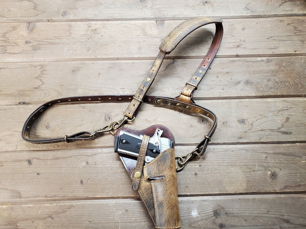 Rustic tanker shoulder holster with silver M1911 in holster on wooden slats.