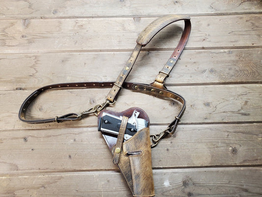 Rustic tanker shoulder holster with silver M1911 in holster on wooden slats.